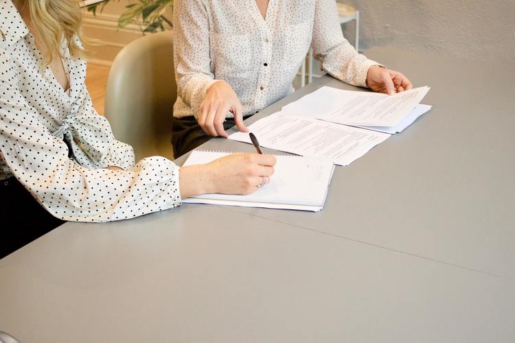 This is an image of two women reading over contracts.